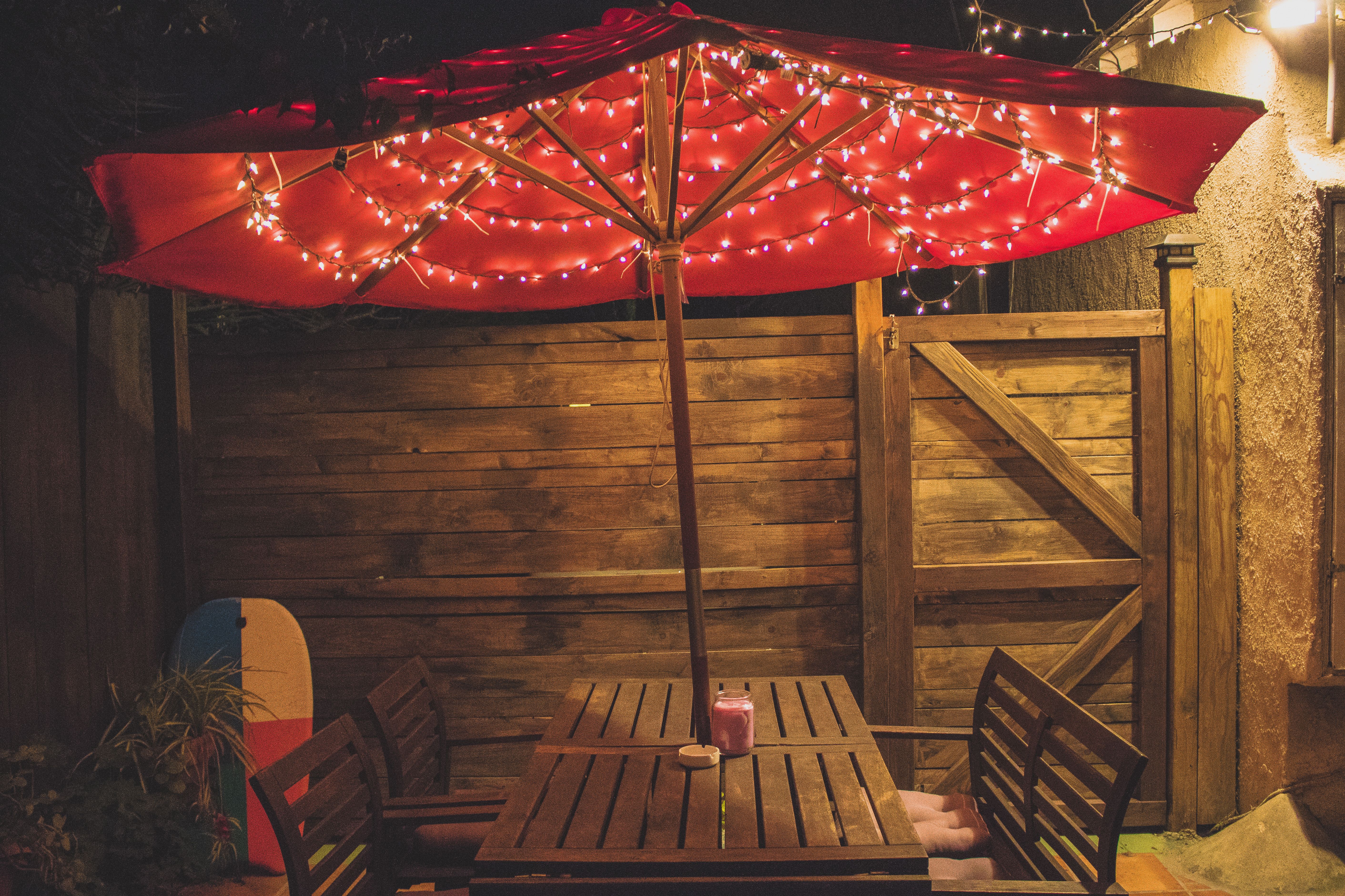 Charming backyard dining area with a red parasol and string lights