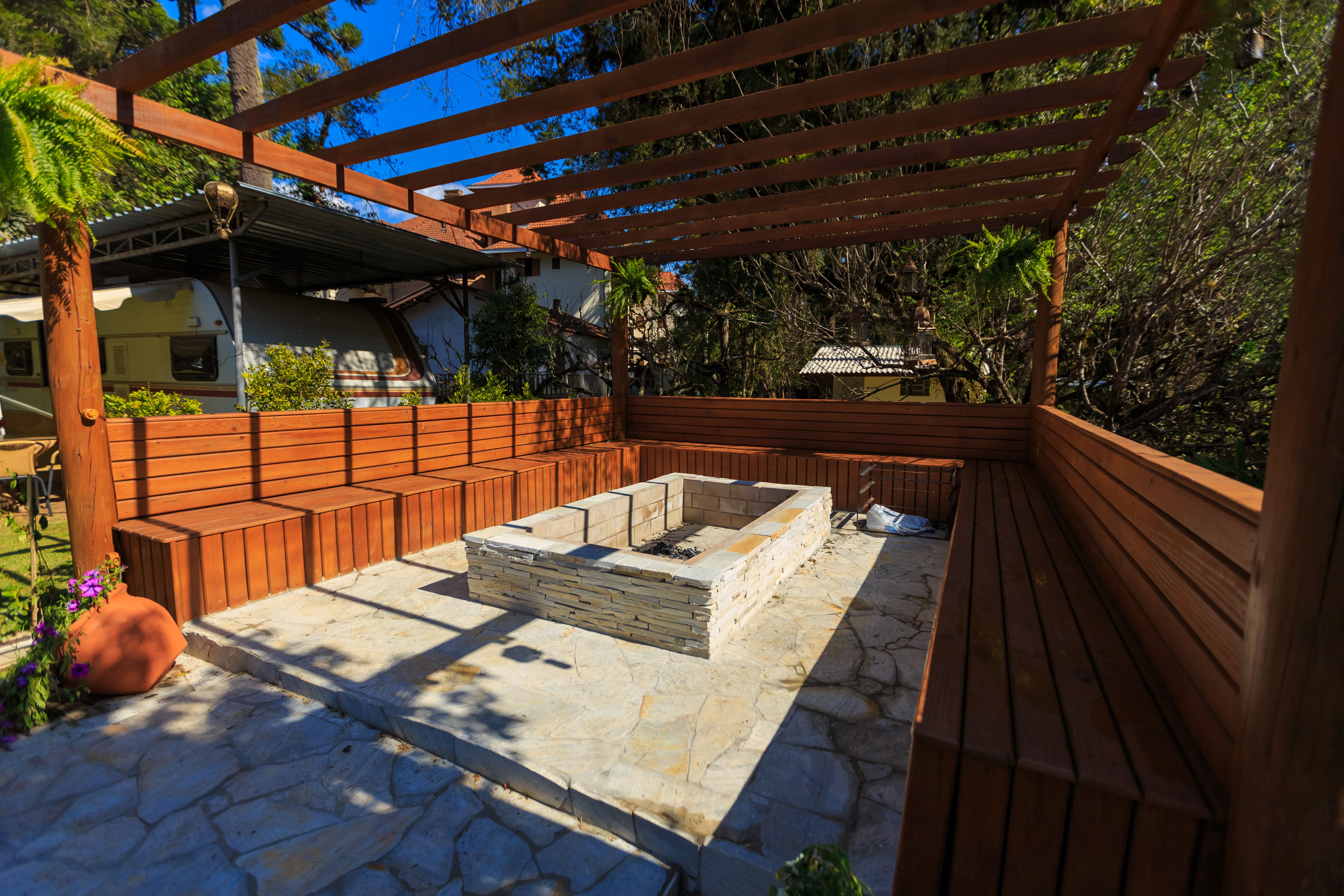 Inviting patio with a stone fire pit and benches beneath a pergola