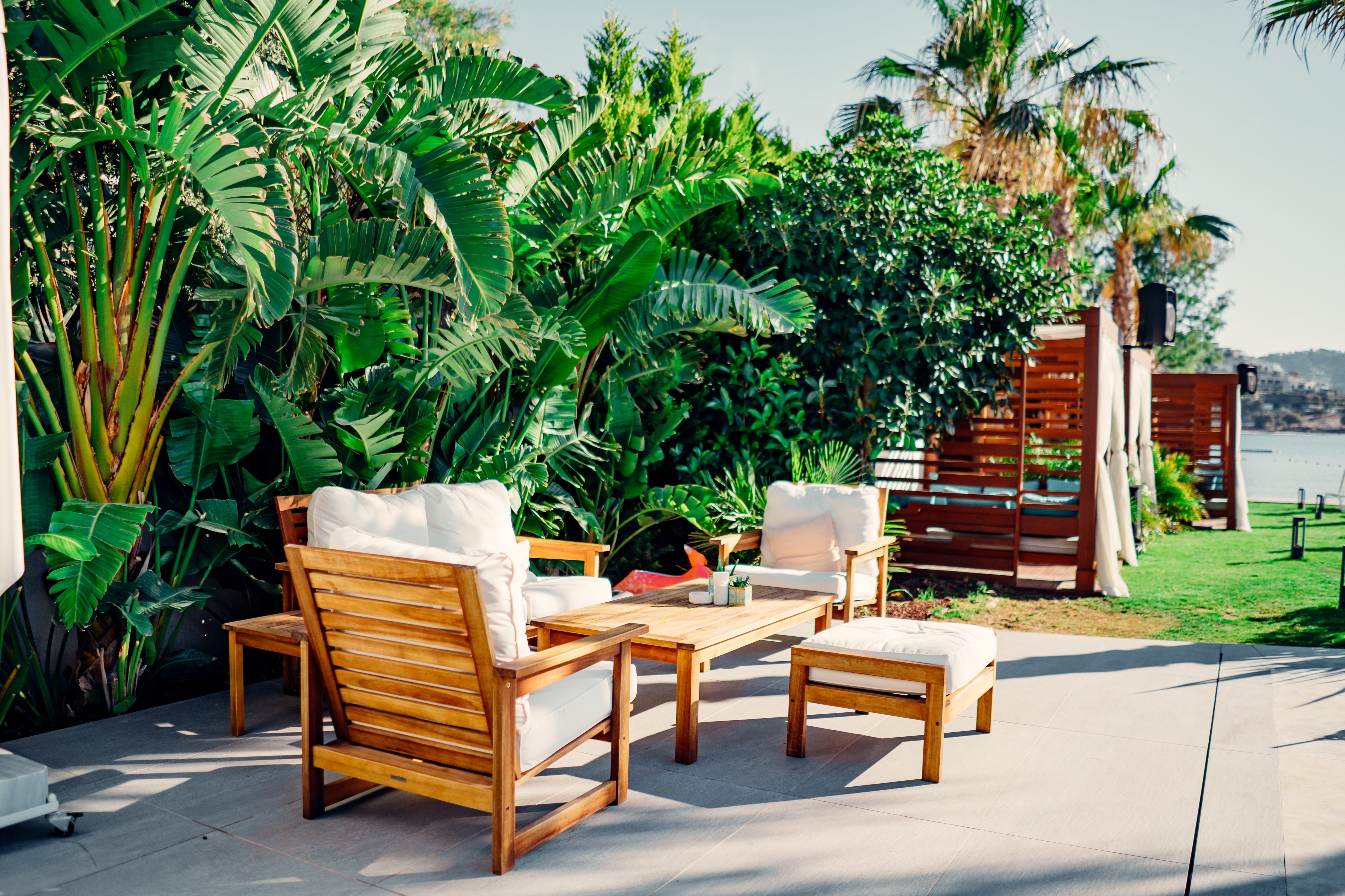Relaxing outdoor patio with wood furniture surrounded by tropical greenery