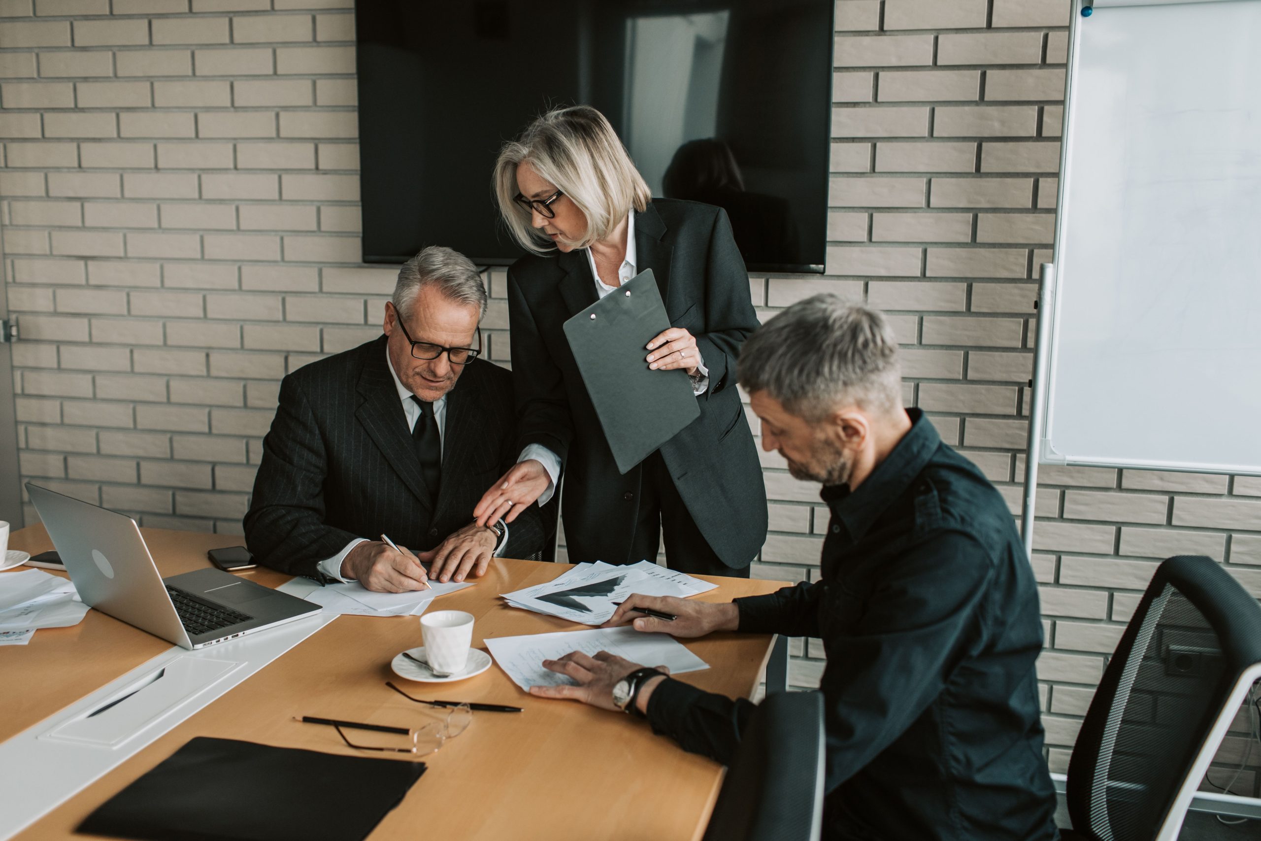Professionals review and sign documents during a confidential business meeting in an office.