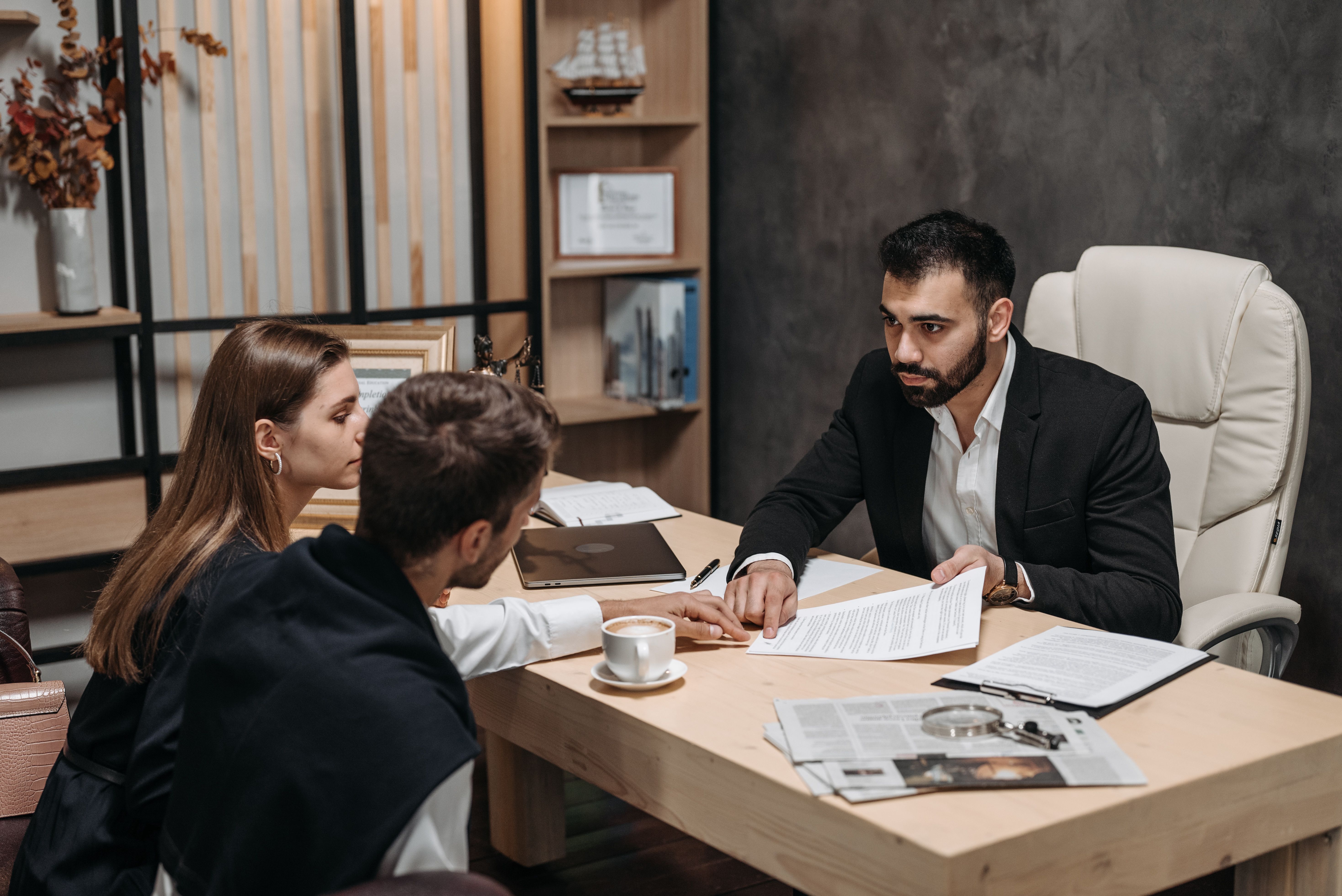 Lawyer discusses private legal documents with clients at an office desk.