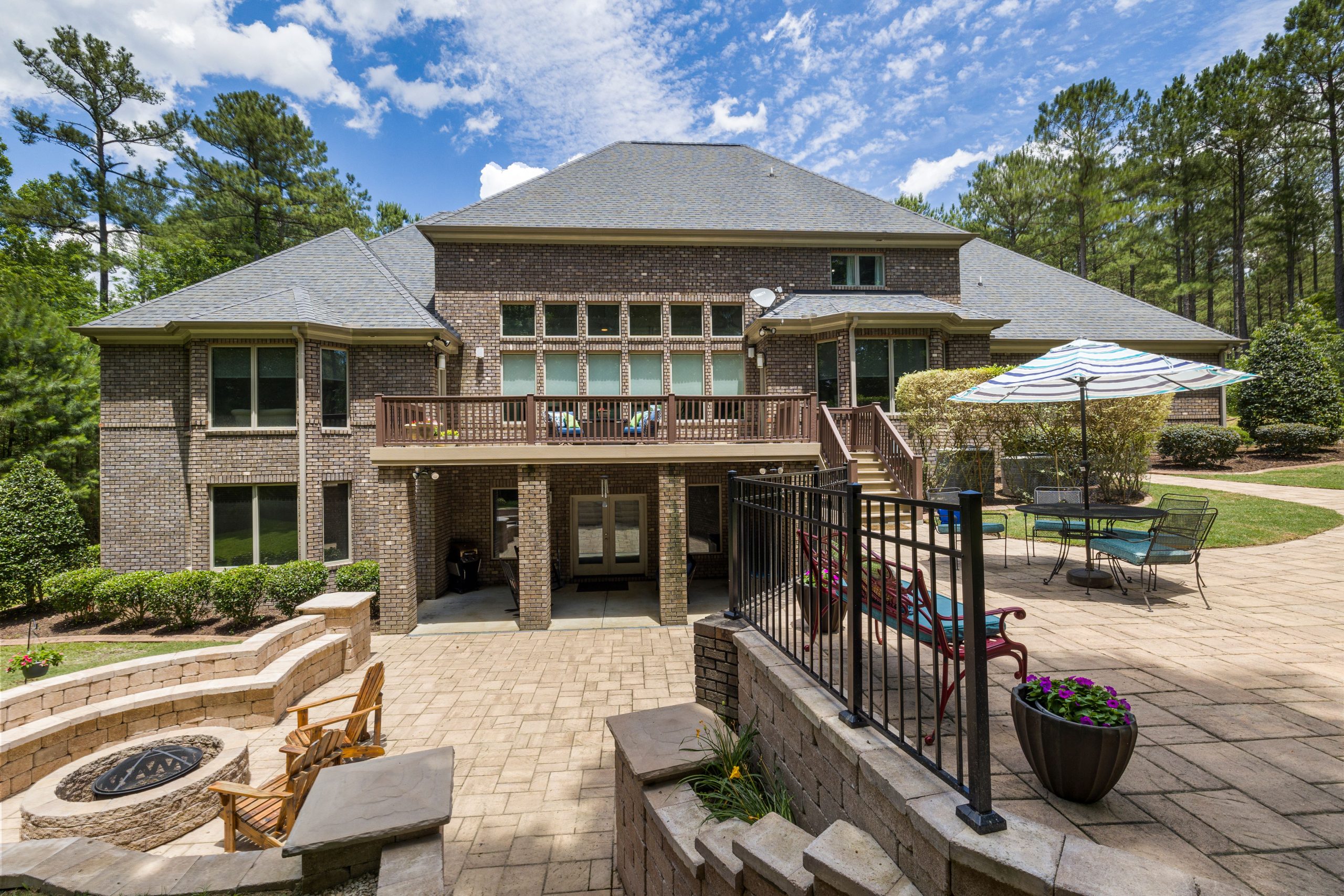 Luxury brick home with a large terrace, fire pit, and well-maintained backyard garden